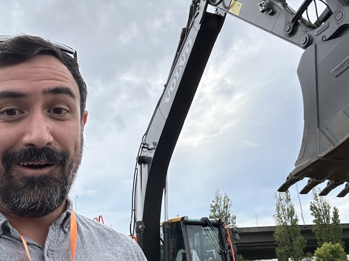 Decorative: John Anderson in front of an electric excavator looking excited.