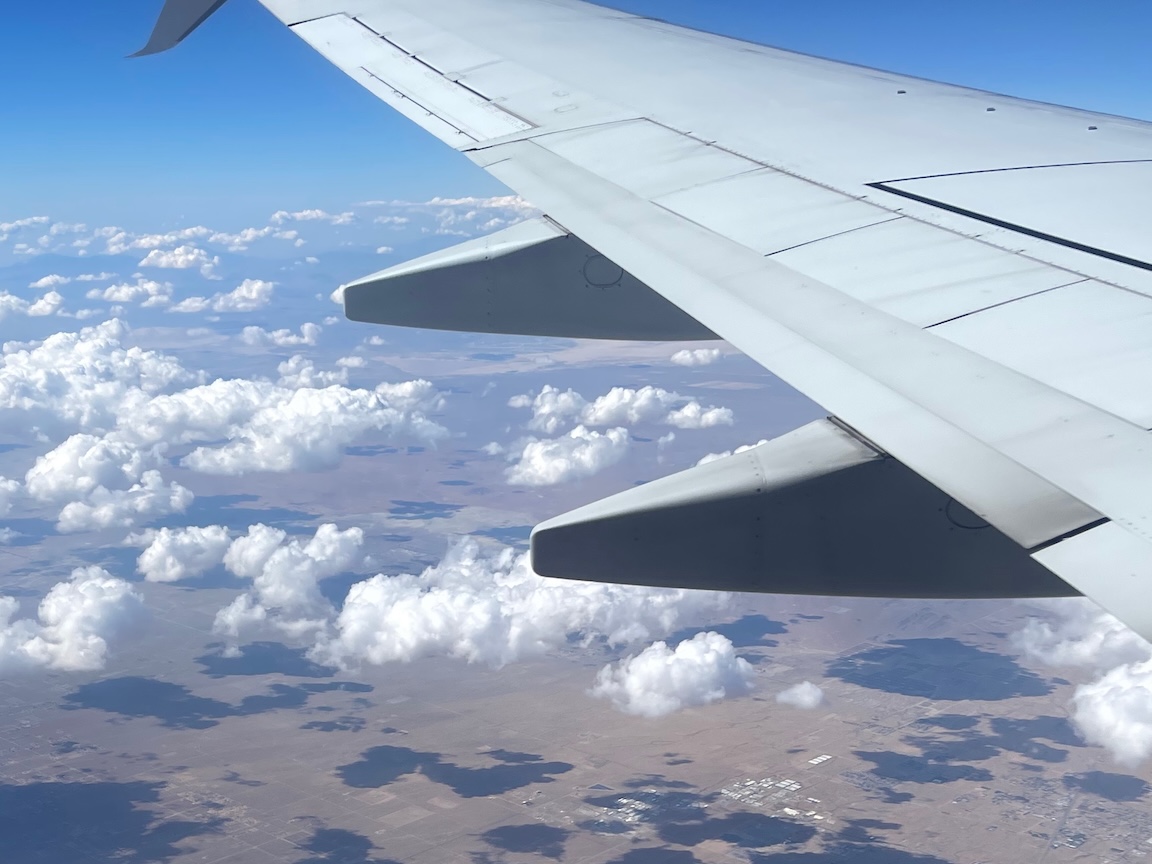 Decorative: Looking out a plane window at a wing with farmland beneath the plane.